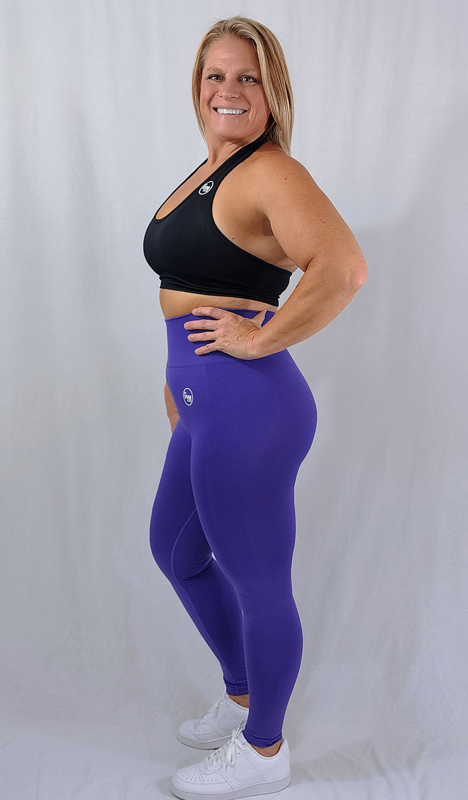 Gym Brand Apparel purple leggings and black halter sports bra side view.