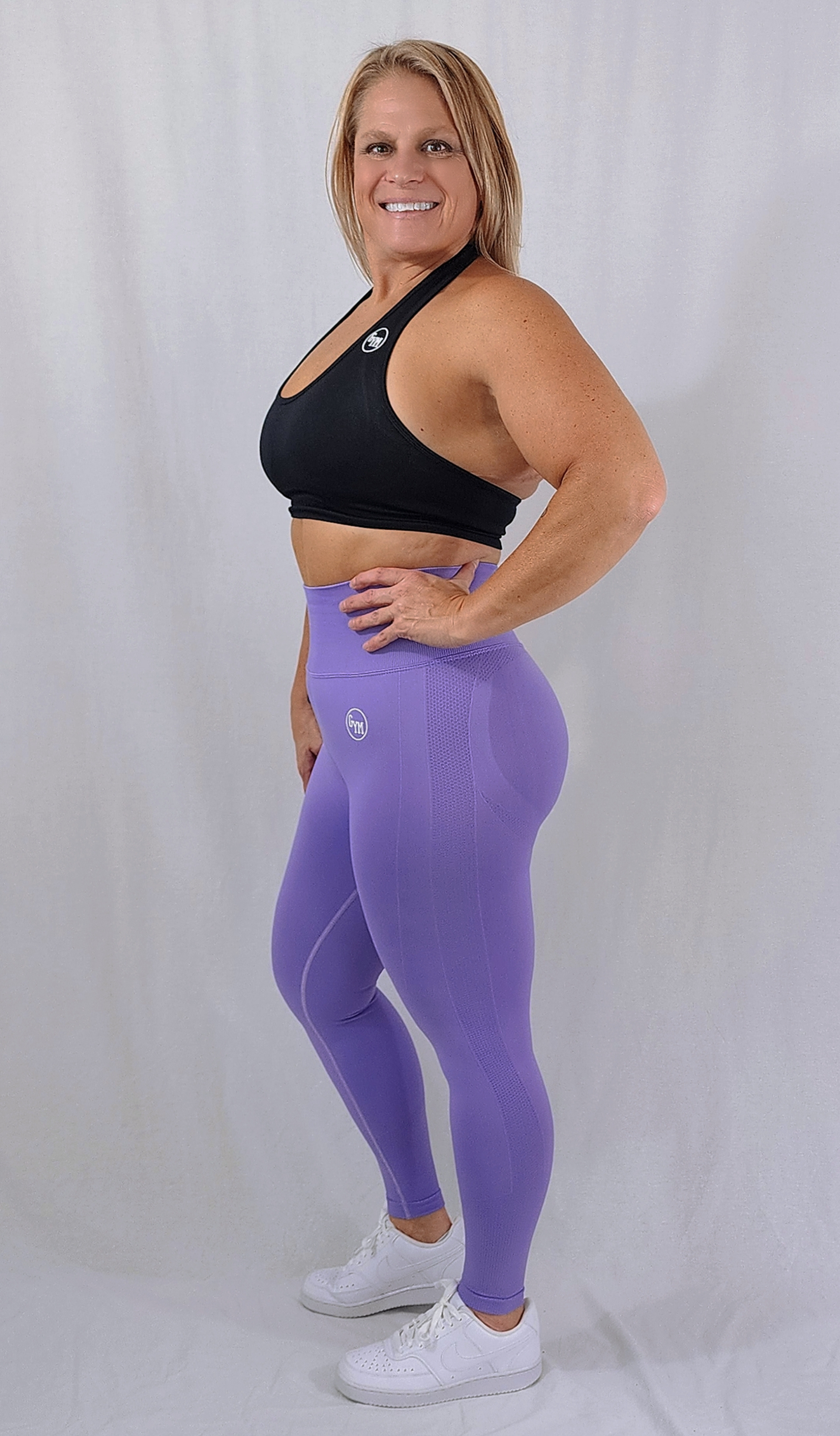 Gym Brand Apparel purple leggings and black halter sports bra side view.